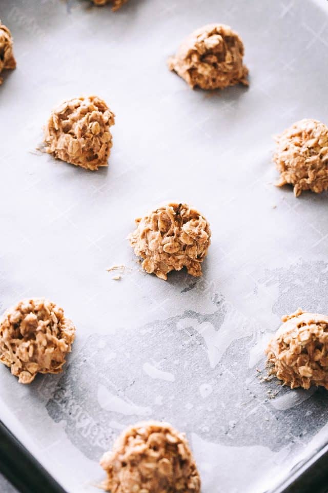 Apple oatmeal cookie dough balls on a parchment-lined baking sheet.