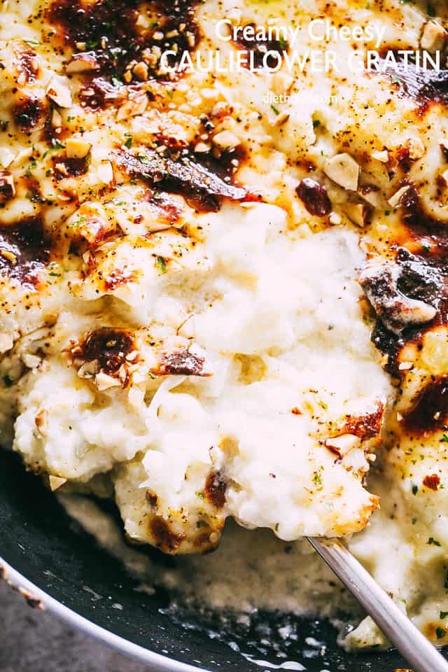 Close up of cauliflower gratin in a skillet with a spoon for serving.