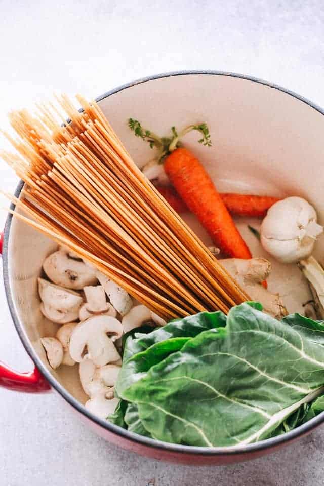 Swiss chard, noodles, carrots, and mushrooms inside of a Dutch oven.