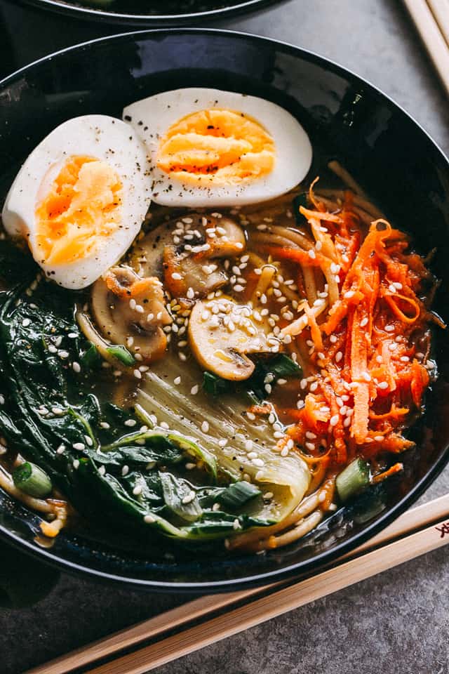 Easy Soba Noodle Soup served in a bowl and garnished with halved boiled eggs, sesame seeds, and mushrooms.