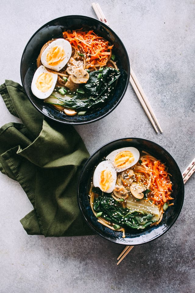 Overhead image of soba noodle soup, served in black bowls.