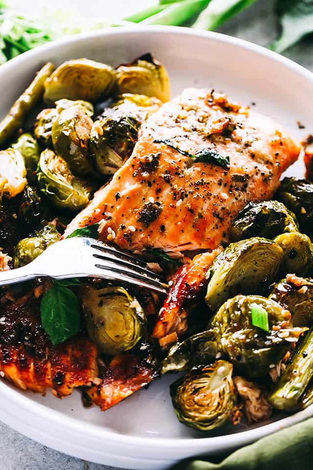 Ginger glazed salmon on a plate with brussels sprouts and asparagus. 