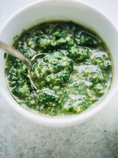 Parsley pesto in a white bowl with a spoon.