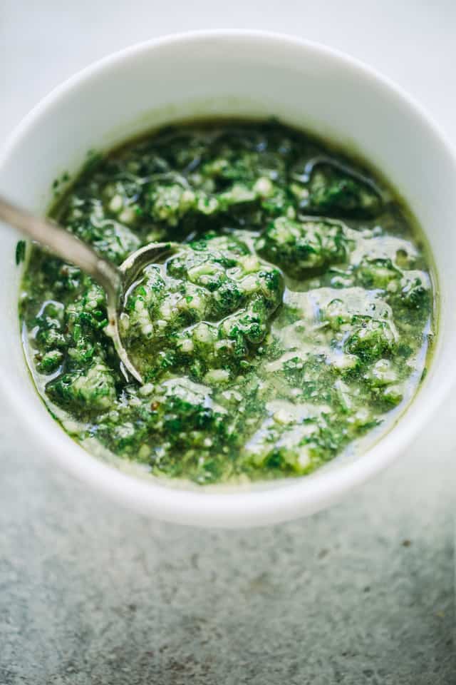 Parsley pesto in a white bowl with a spoon.
