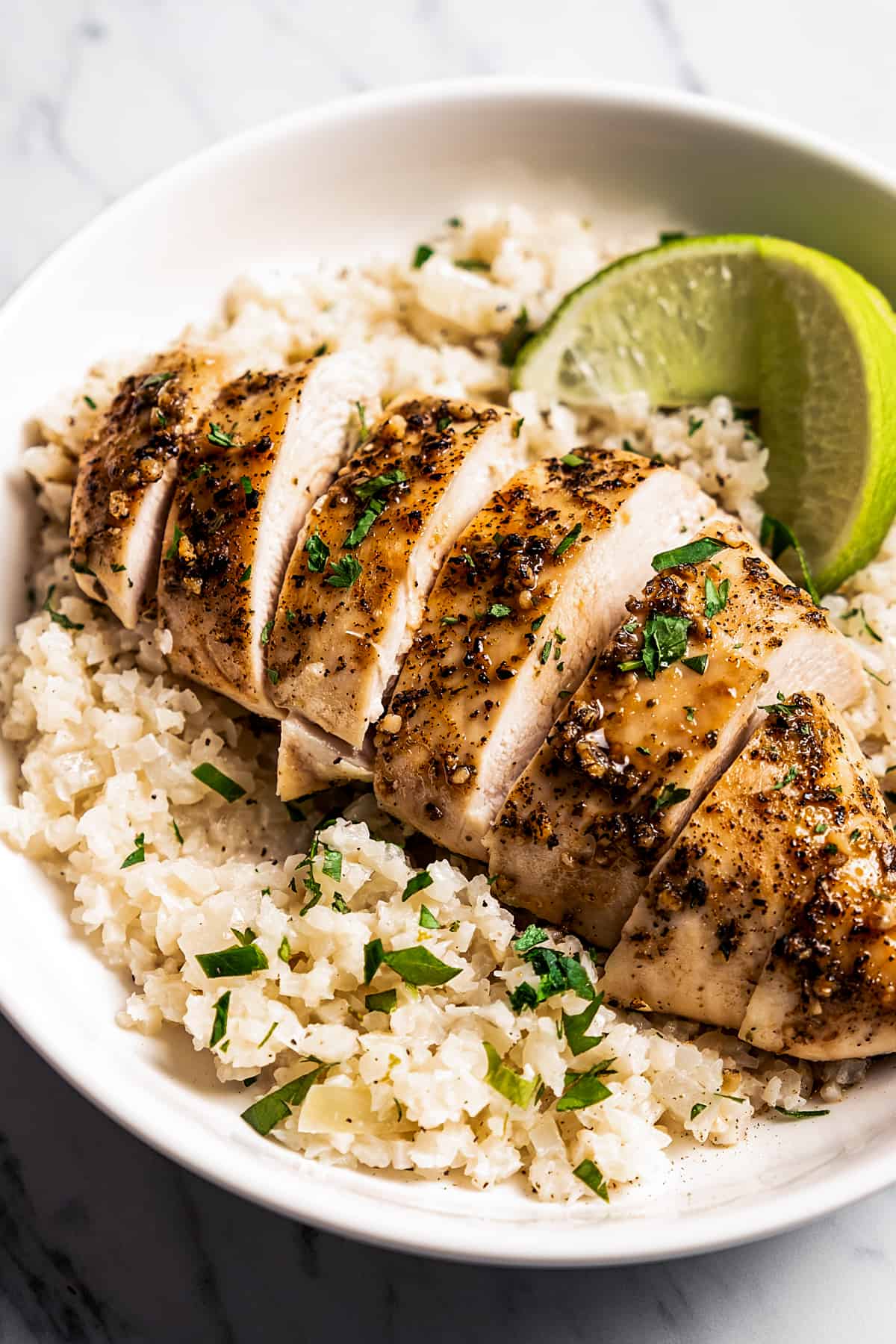 Bowl of rice topped with sliced baked chicken breast