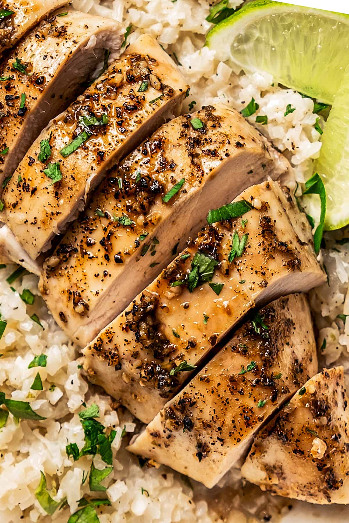 Closeup of sliced baked chicken breast over rice