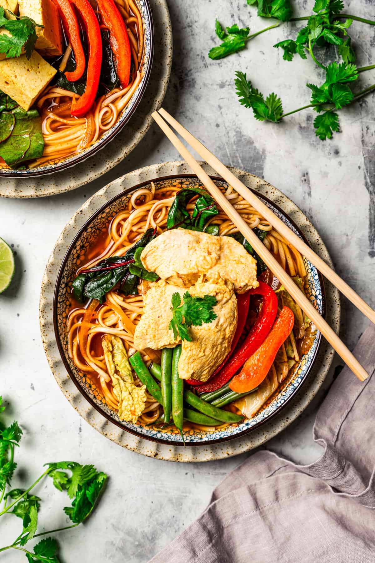 Overhead view of a bowl of noodles and broth topped with Chinese hot pot ingredients, with a set of chopsticks resting on the edge of the bowl.