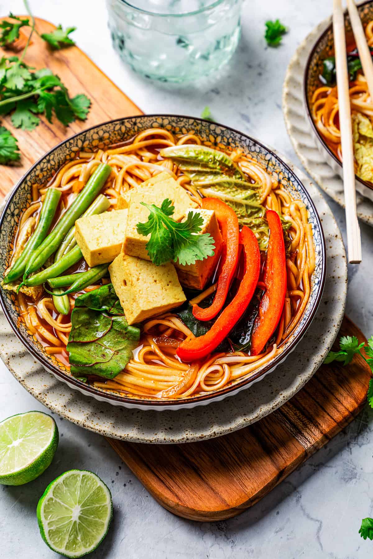 Overhead view of a bowl of noodles and broth topped with Chinese hot pot ingredients on a wooden board.