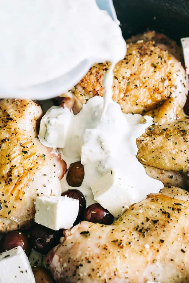 Pouring cream sauce over chicken thighs in a skillet.