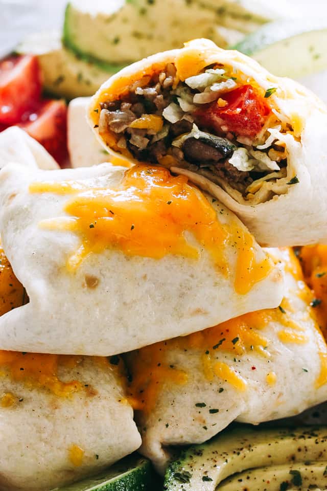 beef burritos stacked up on a plate.
