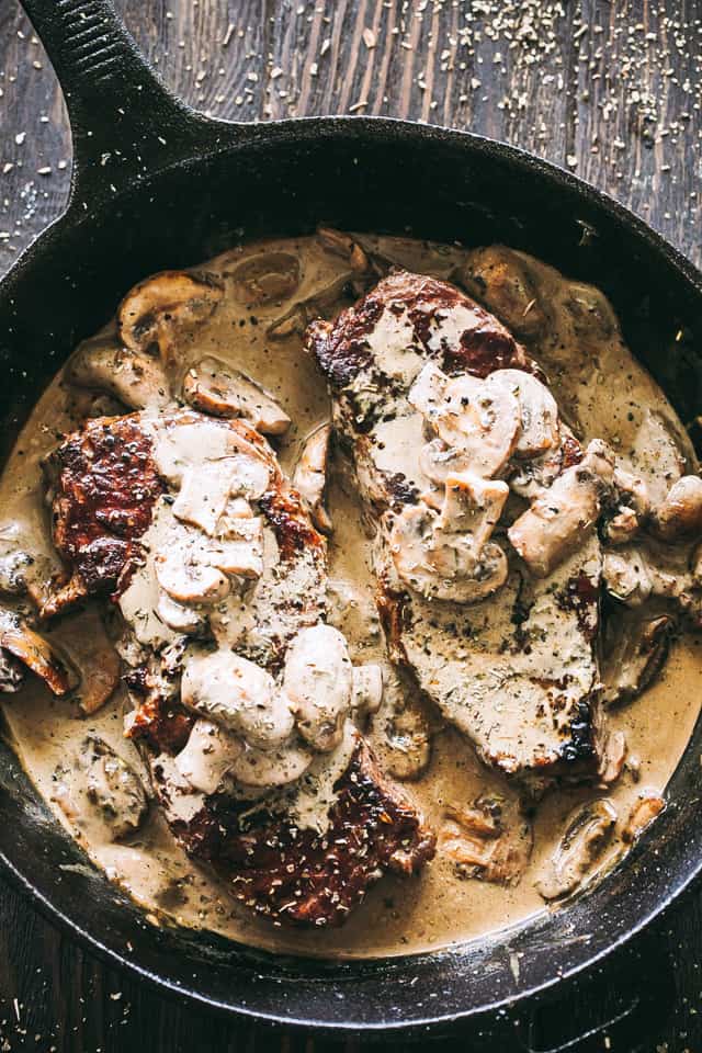 Overhead view of steak with mushroom sauce in a cast iron skillet.