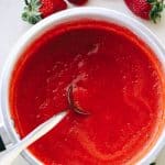Overhead view of strawberry sauce in a bowl with a spoon.
