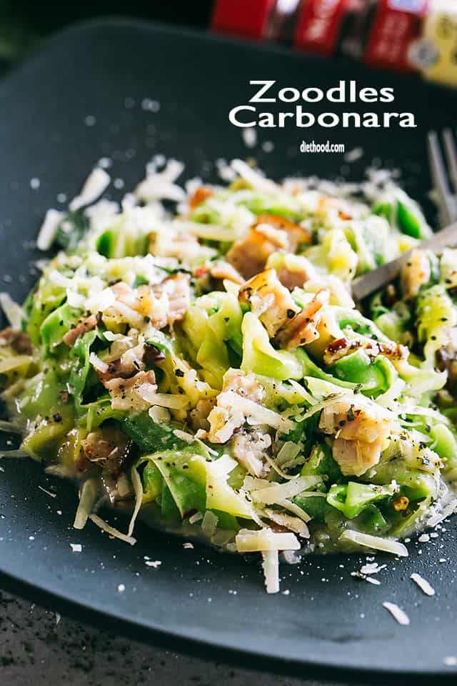 Zucchini carbonara served on a dark dinner plate.