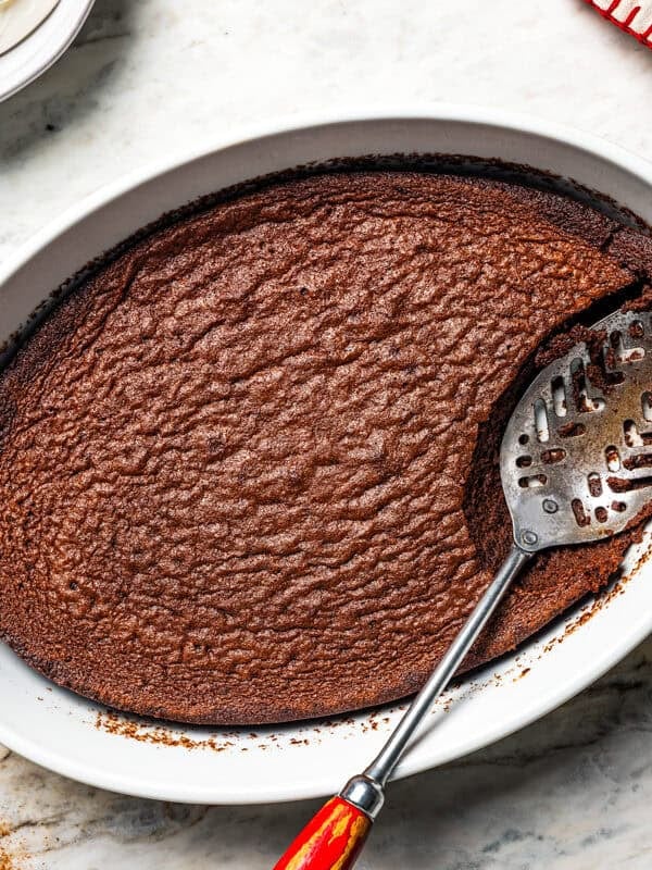 Overhead view of a spoon scooping from a chocolate fudge cake in a baking dish.