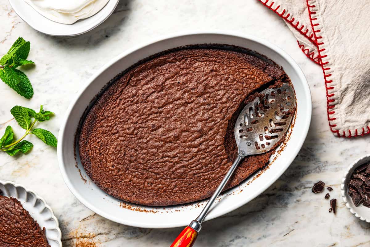 Overhead view of a spoon scooping from a chocolate fudge cake in a baking dish.