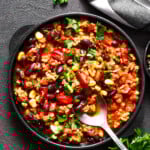 Overhead image of a burrito bowl in a dinner plate topped with chopped peppers and fresh cilantro.