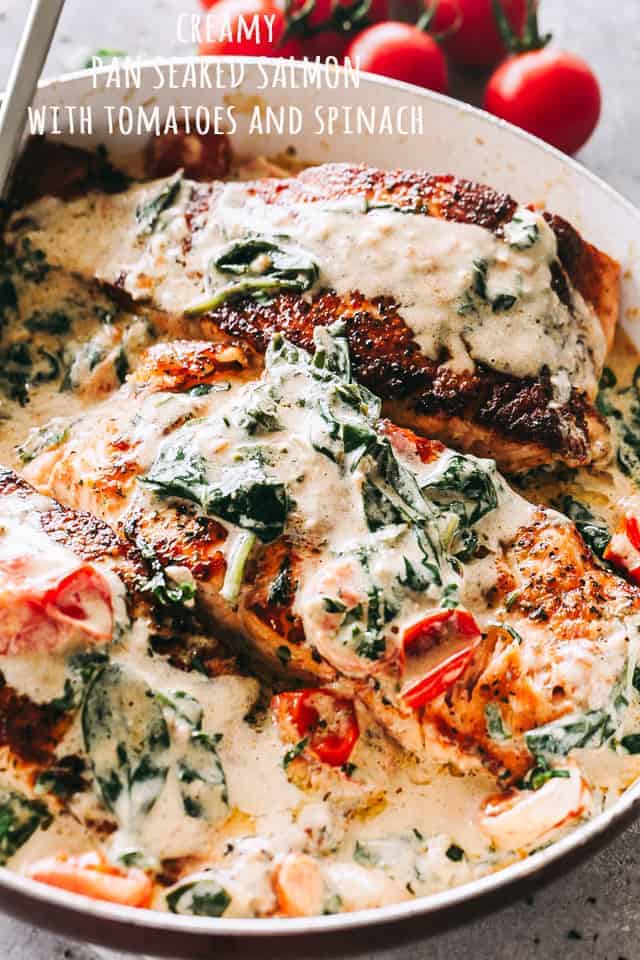 Salmon fillets drizzled with creamy sauce and topped with cooked spinach and tomatoes.