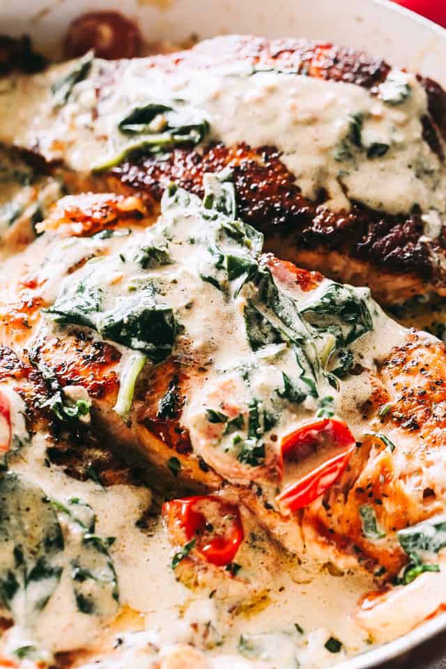 Pan Seared Salmon with Tomatoes and Spinach - Quick and easy pan-seared salmon is smothered in a flavorful creamless creamy sauce prepared with evaporated milk, tomatoes, and baby spinach.