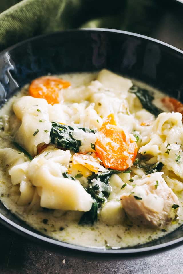 Close-up of tortellini soup served in a black soup bowl.