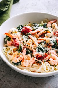 Creamy Shrimp Fettuccine with Spinach and Tomatoes Recipe - For a quick and delicious weeknight dinner, whip up this shrimp fettuccine coated in a light and creamy sauce prepared with spinach and cherry tomatoes! 