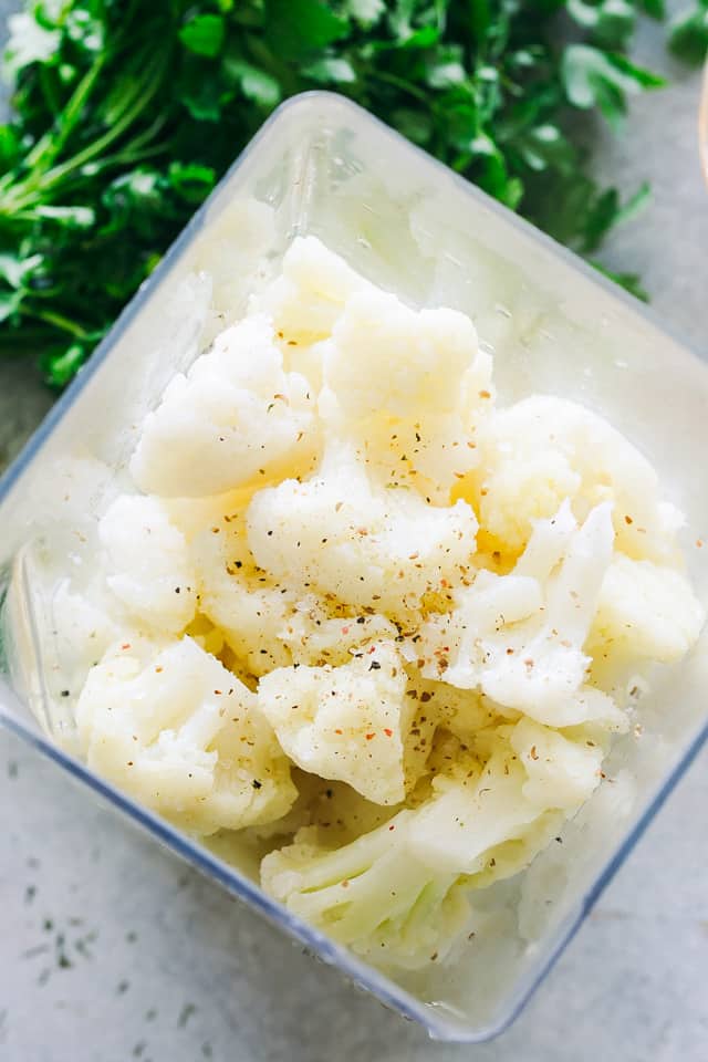 Cheesy, garlicky loaded cauliflower cooked in the Instant Pot! Low-carb and delicious, this easy cauliflower mash tastes like loaded potatoes. Overhead view of cooked cauliflower inside a blender.