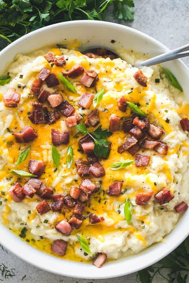 Instant Pot Mashed Cauliflower served in a large white bowl and topped with melted cheese and diced bacon.