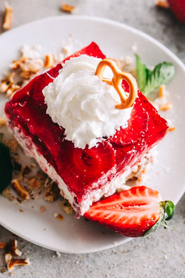 Close up image of Strawberry Pretzel Dessert square served on a dessert dish and garnished with cream.