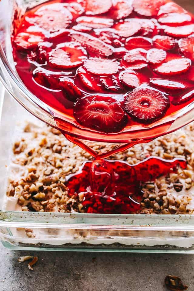 Pouring strawberry gelatin over pretzel crust.