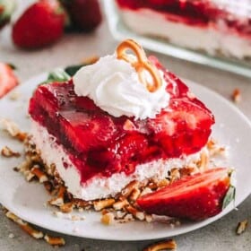 Strawberry Pretzel Dessert square served on a dessert dish and garnished with cream.