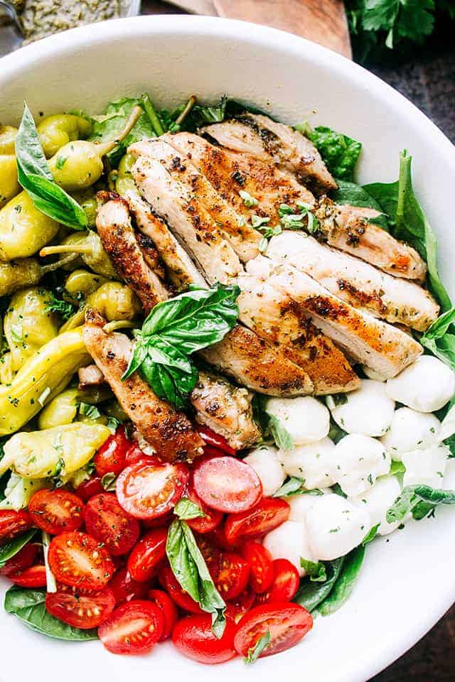 Antipasto Salad with Grilled Chicken and Basil Pesto Vinaigrette - Fresh and delicious salad packed with grilled chicken, mozzarella cheese, tomatoes, and pepperoncini, all tossed in an amazing homemade Basil Pesto Vinaigrette.