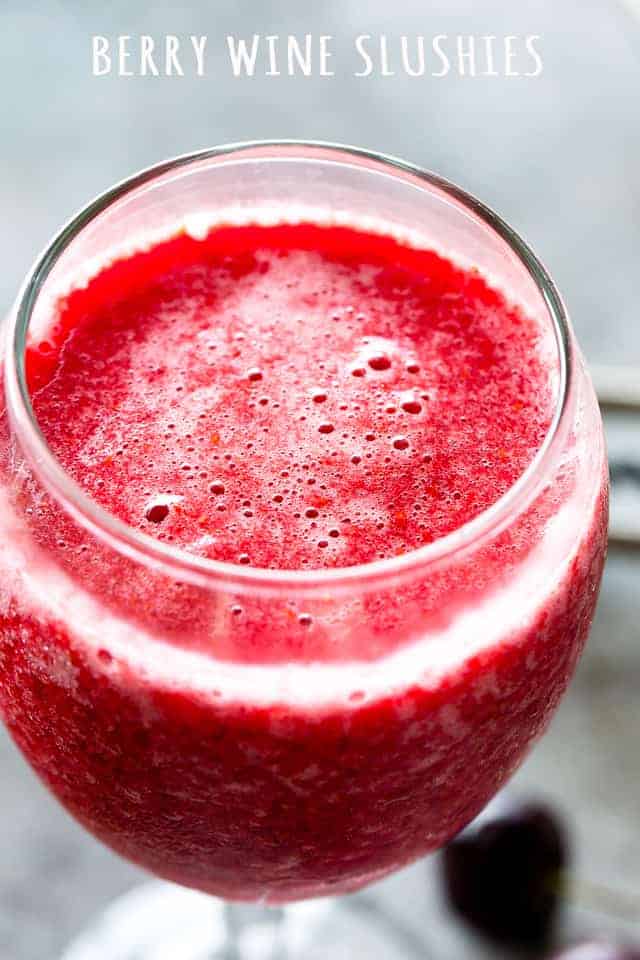 An up-close image of a wine-drinking glass filled with a mixture of frozen berries and wine.