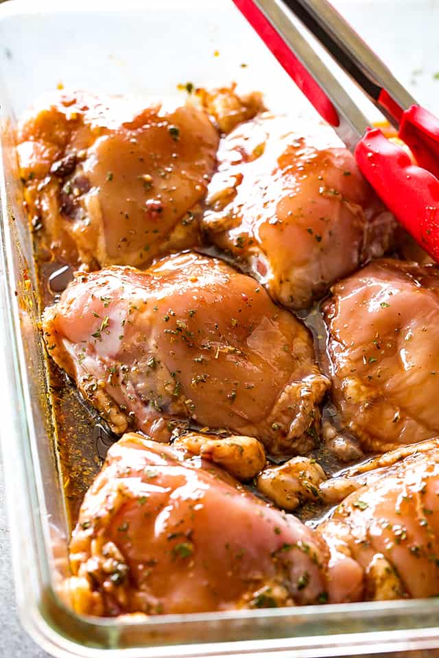 chicken thighs marinating in a glass dish.