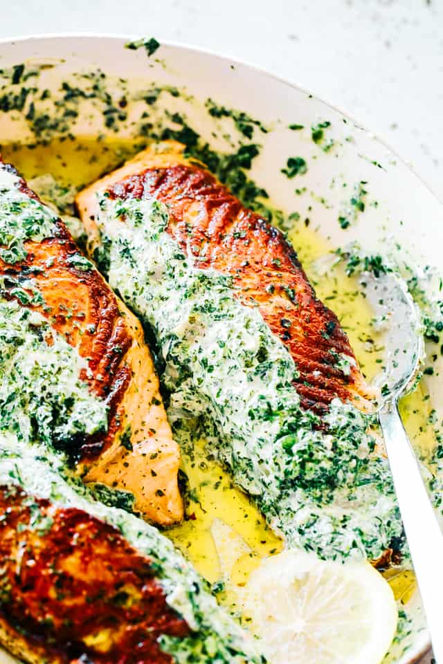 Spinach artichoke dip stuffed Salmon fillets in a skillet.