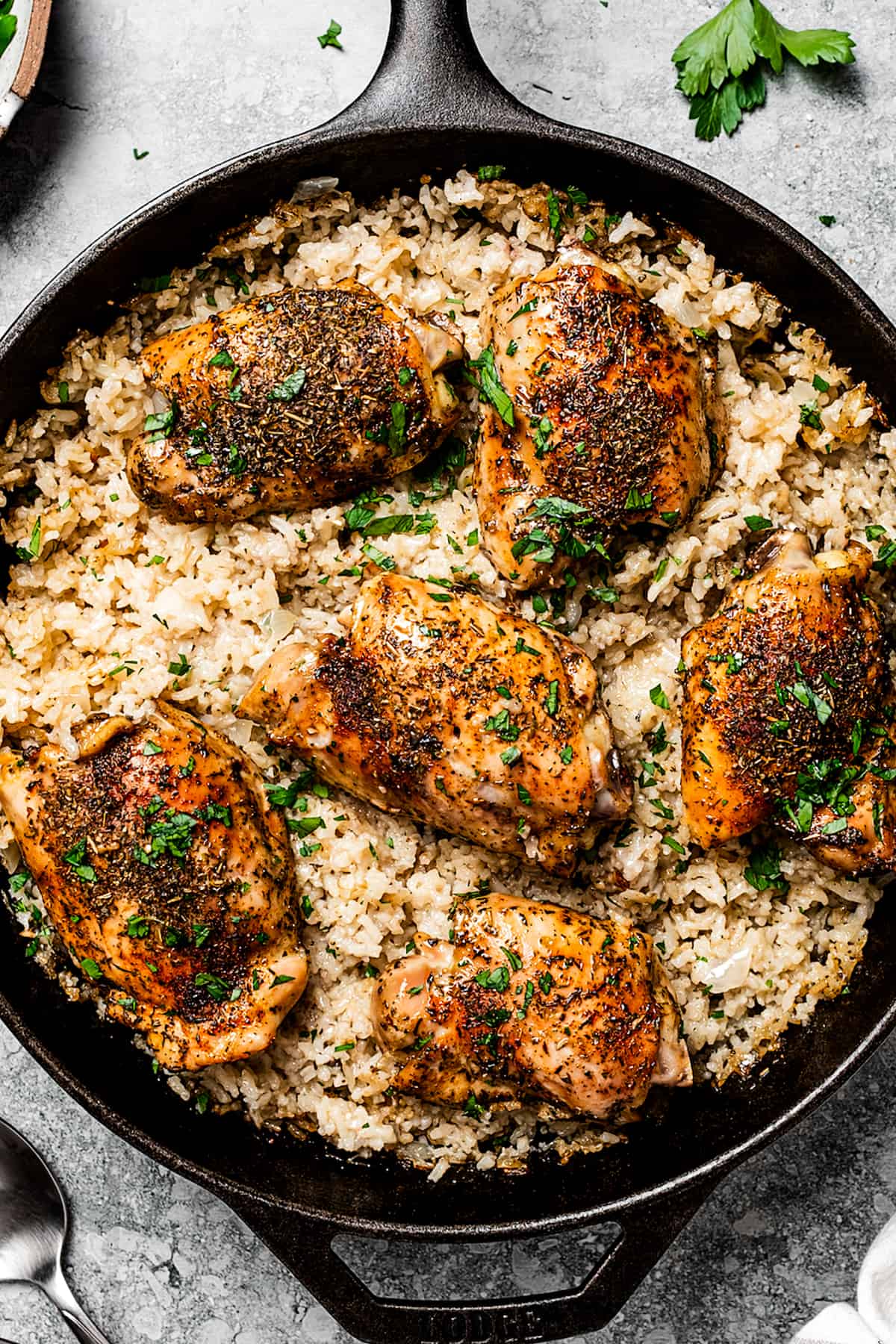 a skillet with cooked garlic butter chicken with rice and garnished with parsley.