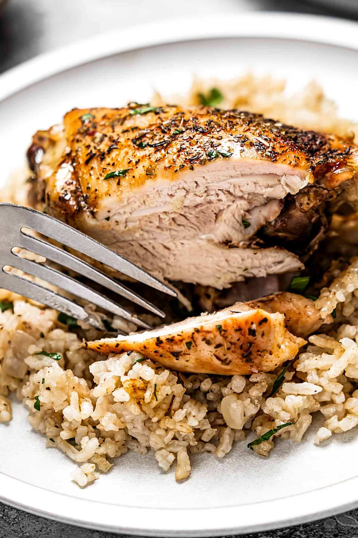 A fork with rice and chicken on a plate.