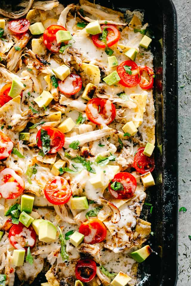 nachos topped with balsamic chicken, avocados, tomatoes, and cheese.