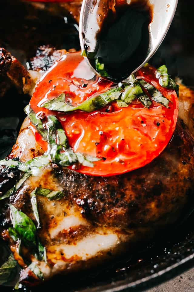 Caprese Pork Chops - Seared juicy caprese pork chops marinated in a garlicky balsamic glaze and topped with sweet tomatoes, melted mozzarella cheese, and fresh basil!