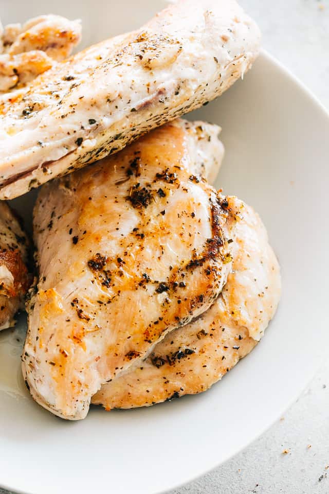 Cooked chicken breasts on a white serving plate.