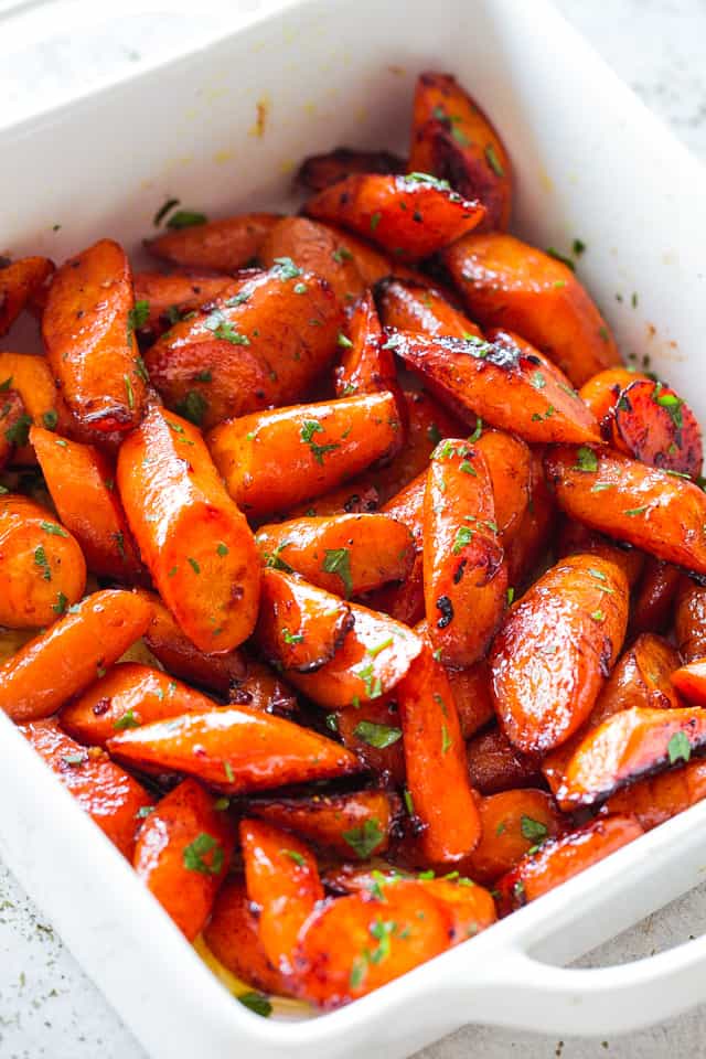 Quartered glazed and roasted carrots in a white baking dish.