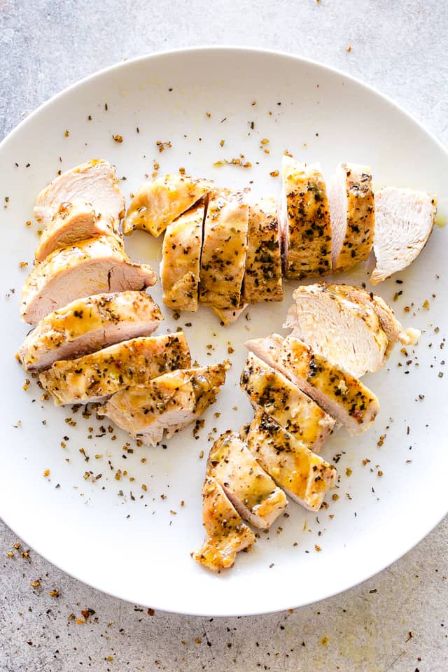 Tender and Juicy Instant Pot Chicken Breasts sliced and arranged on a white dinner plate. 