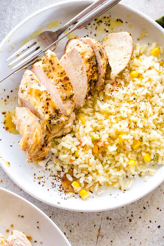 Sliced Chicken Breast served alongside rice topped with corn.