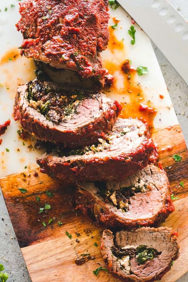 Slices of rolled, stuffed flank steak on a cutting board.
