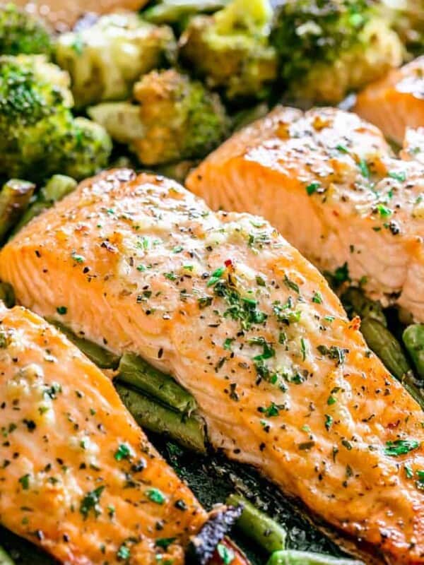 Seasoned salmon fillets baked on a sheet pan over a bed of green vegetables.