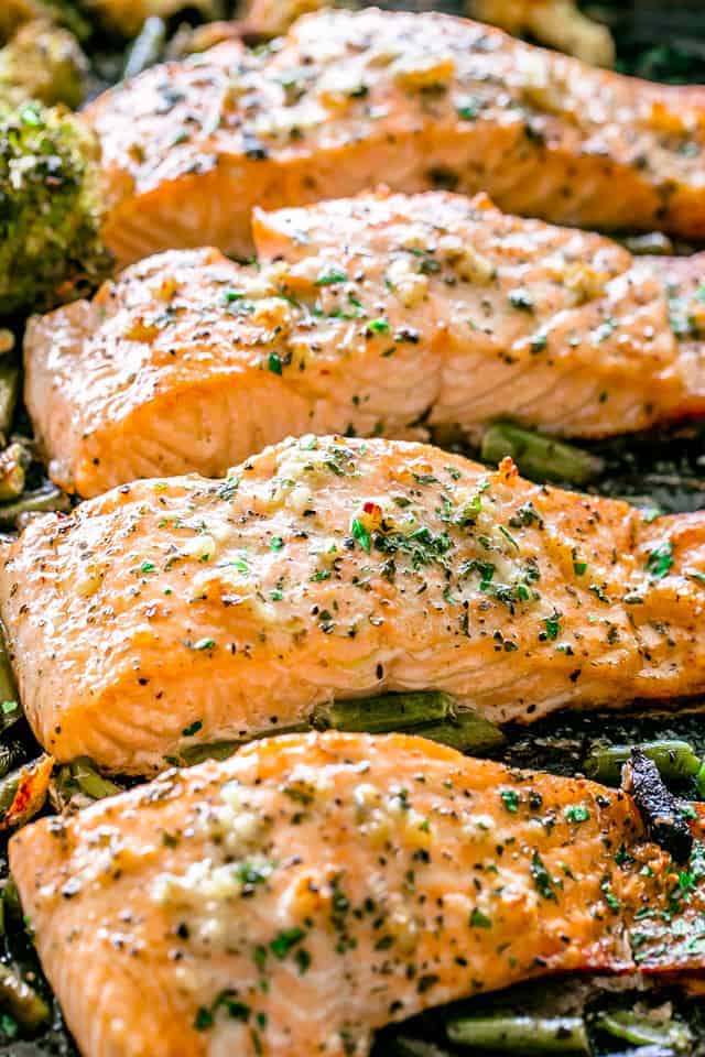 Close-up shot of salmon with vegetables on a sheet pan, to show the texture of the baked fish.