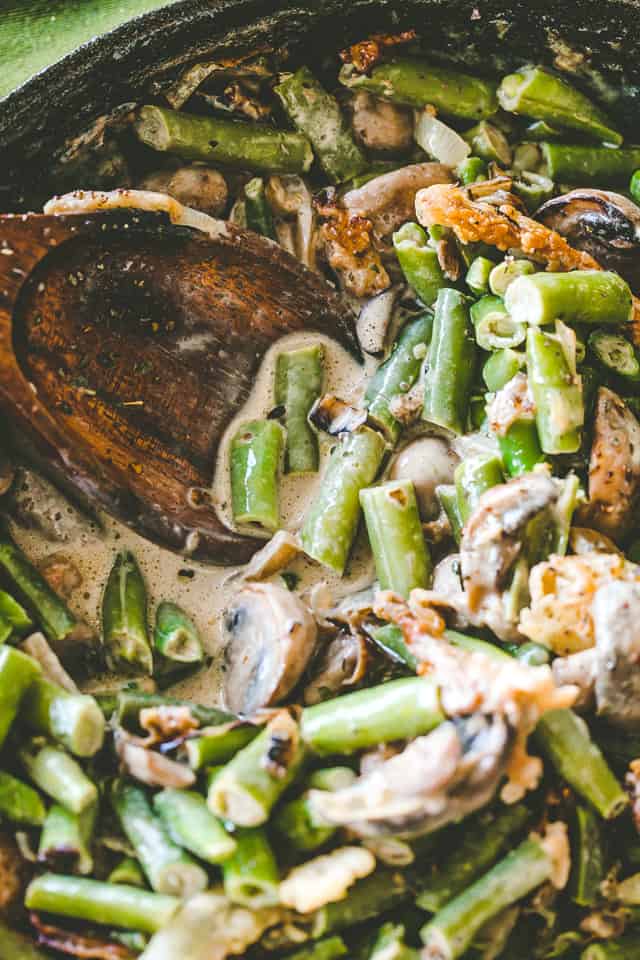 Stirring filling for green bean casserole in a skillet.