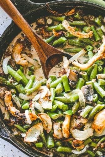 Overhead image of stirring green bean casserole with a wooden spoon.