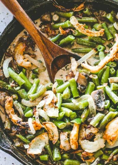 Overhead image of stirring green bean casserole with a wooden spoon.