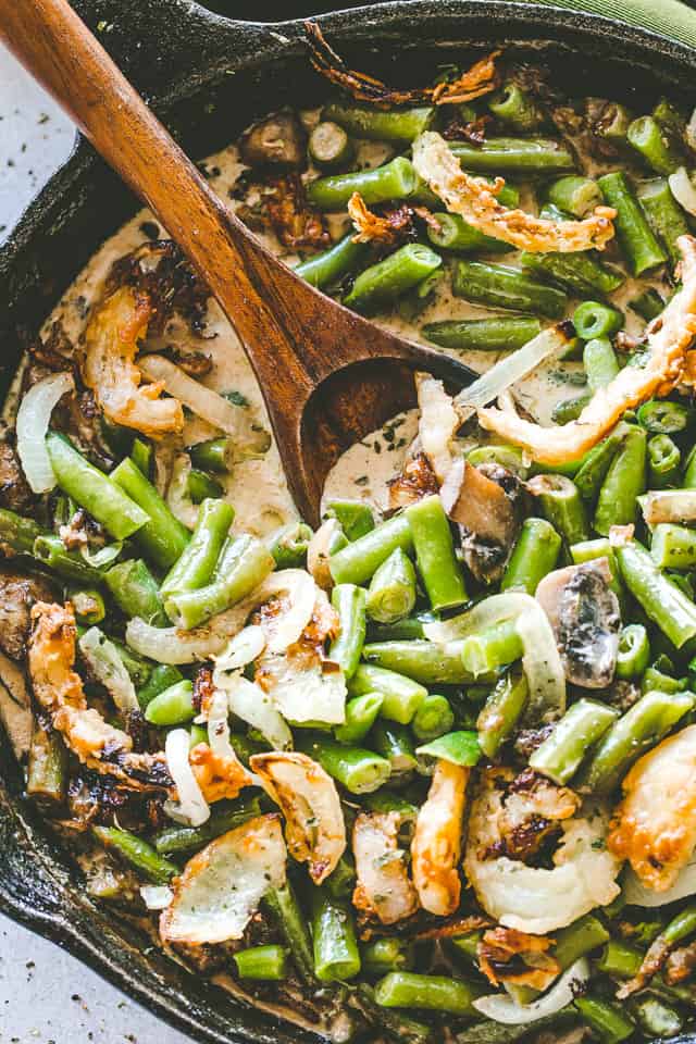 Overhead image of stirring green bean casserole with a wooden spoon.