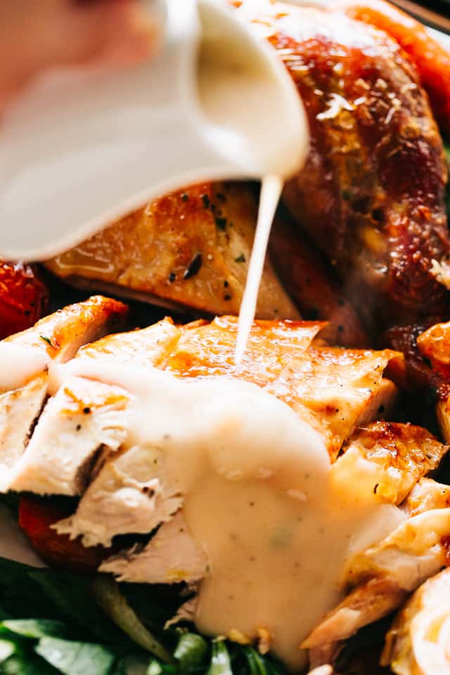 Maple turkey gravy is poured over sliced roast turkey on a plate.