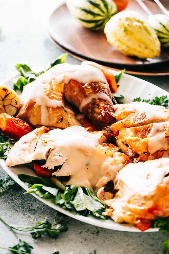 Carved Thanksgiving turkey served over a bed of greens on a platter, topped with maple turkey gravy.